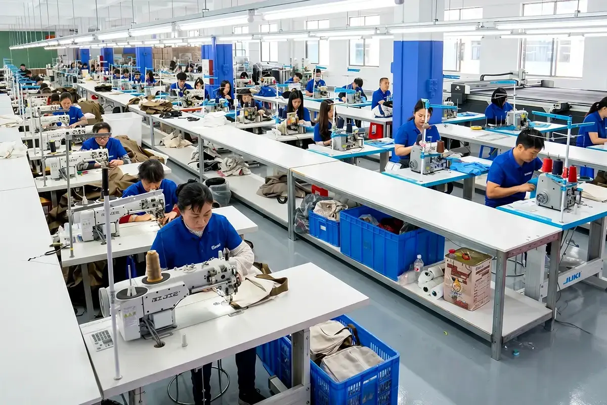 Uniformed workers sewing tote bags in a bright production workshop.