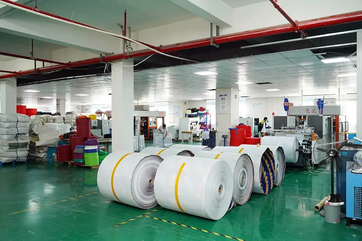 Large fabric rolls staged beside equipment in the material preparation area.