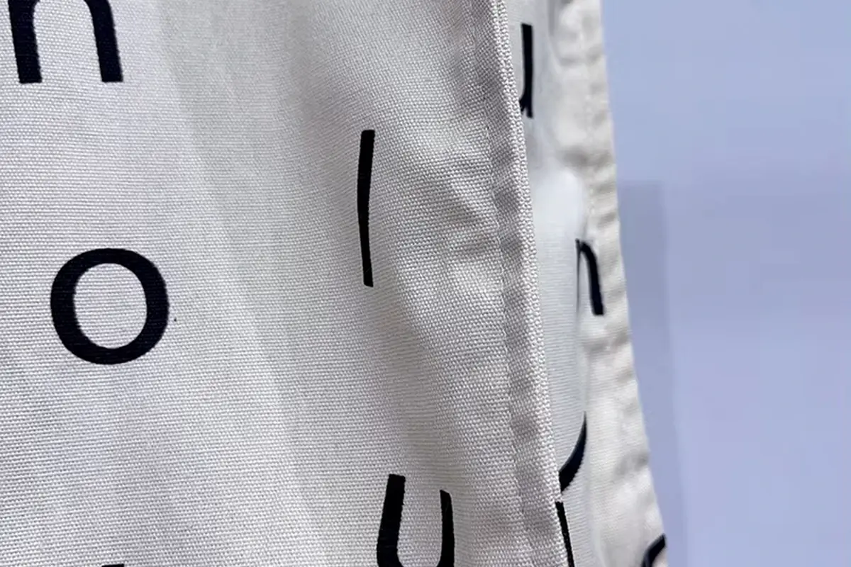 Close-up of printed cotton tote fabric, seams and woven texture.