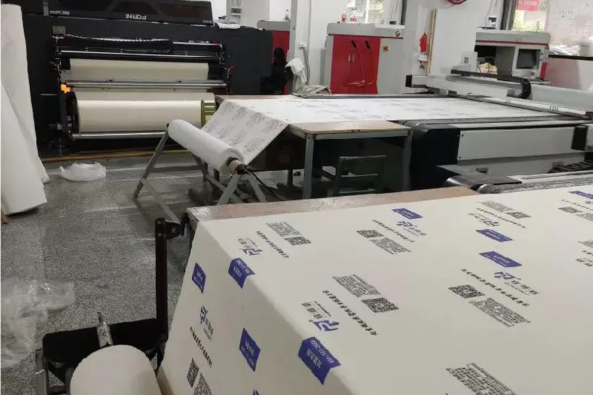 Printed tote bag panels moving through automated production equipment.