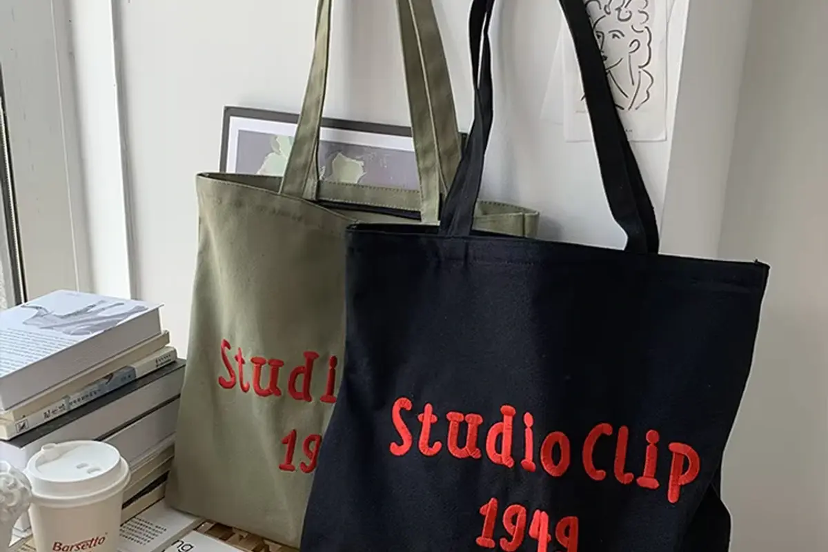 Two canvas tote bags with raised embroidered lettering.