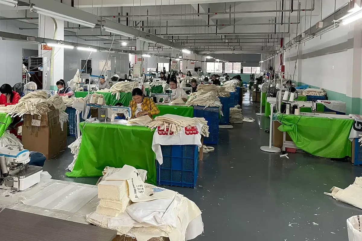 Workers sewing natural cotton tote bags across a busy workshop.