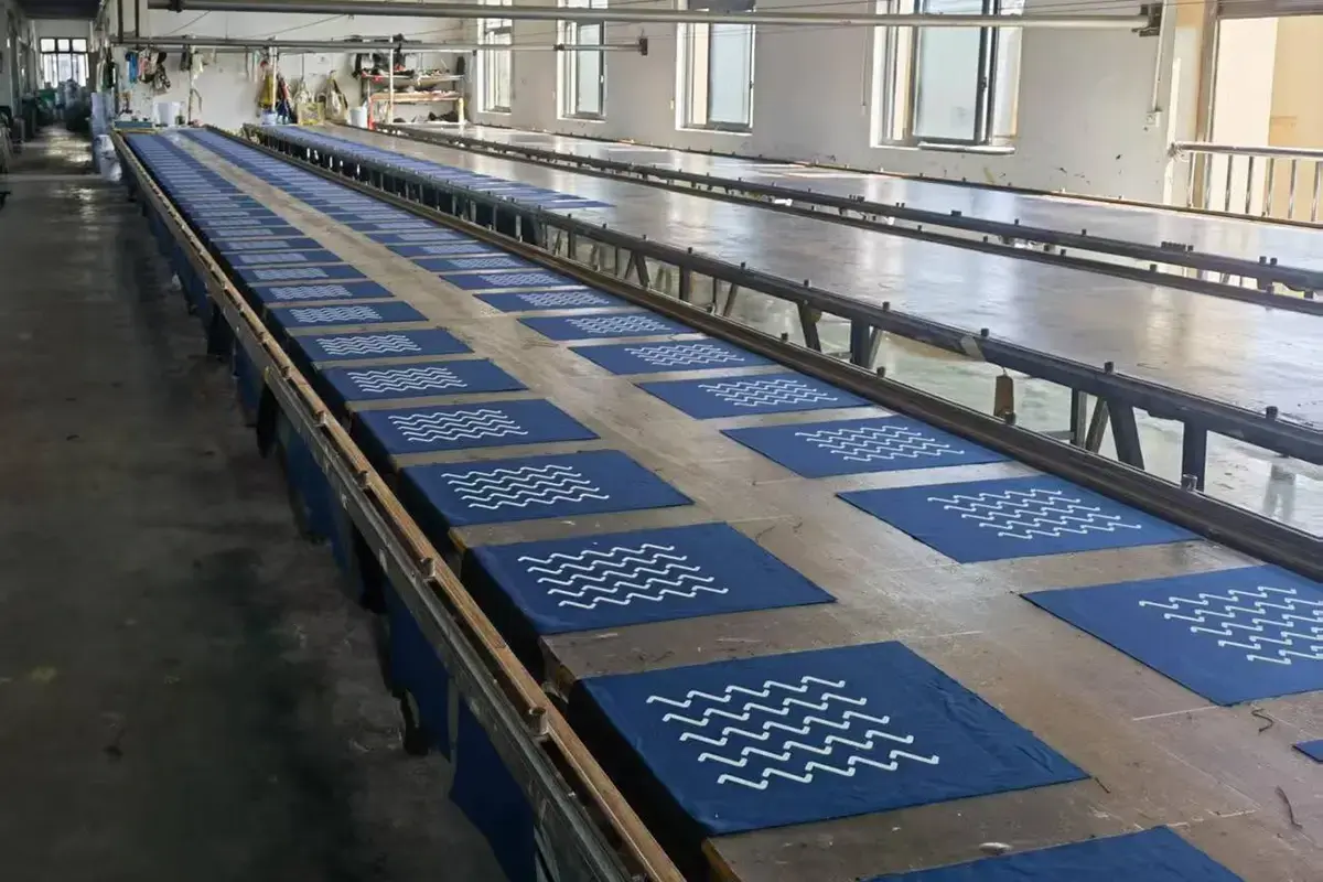 Rows of blue cotton panels drying after white screen printing.