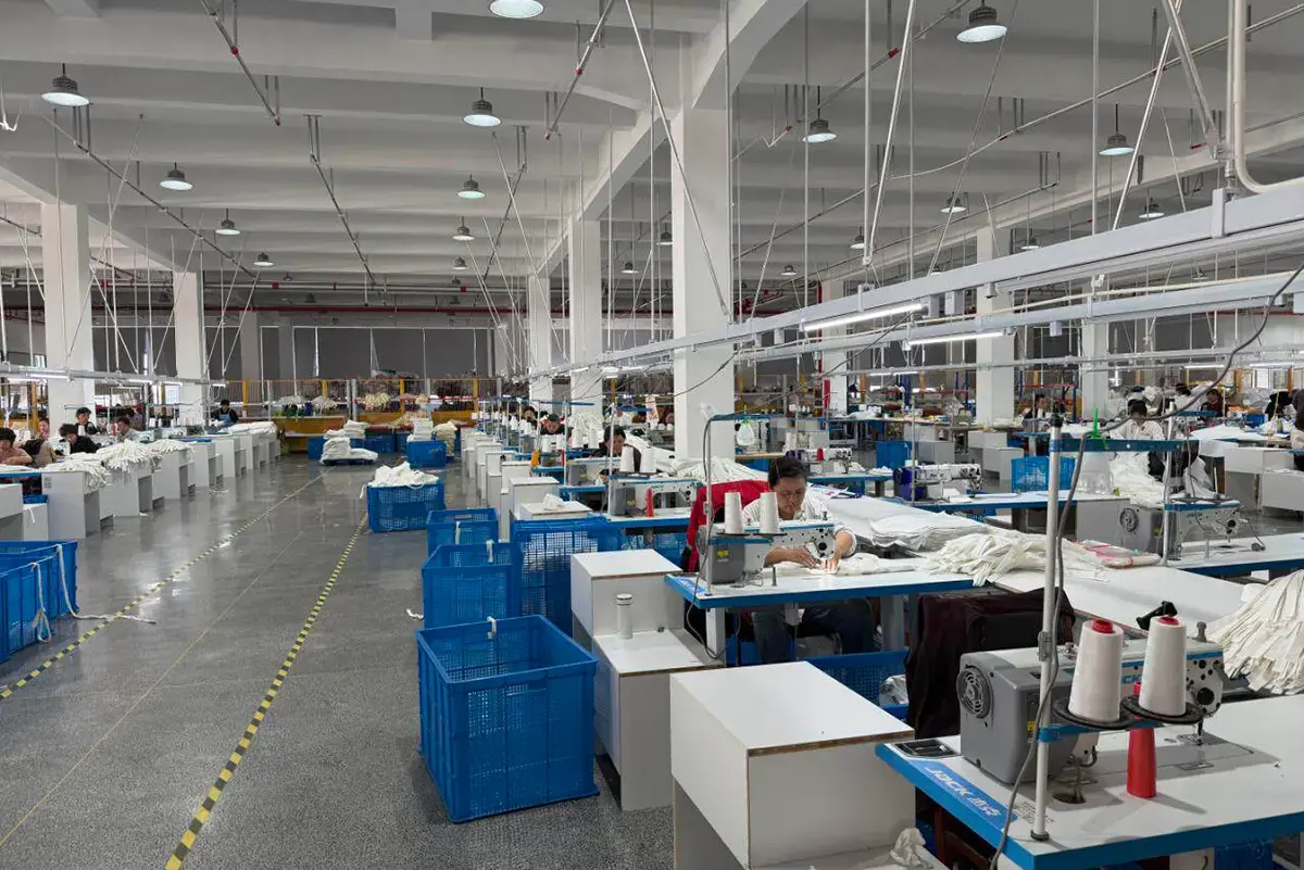 Bright sewing workshop with rows of canvas tote production stations.