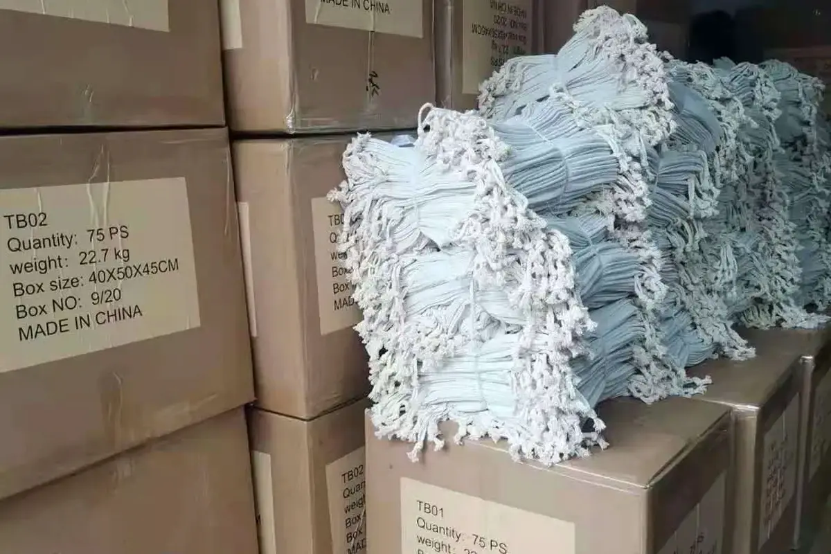 Bundled white tote handles stacked beside labeled shipping cartons.