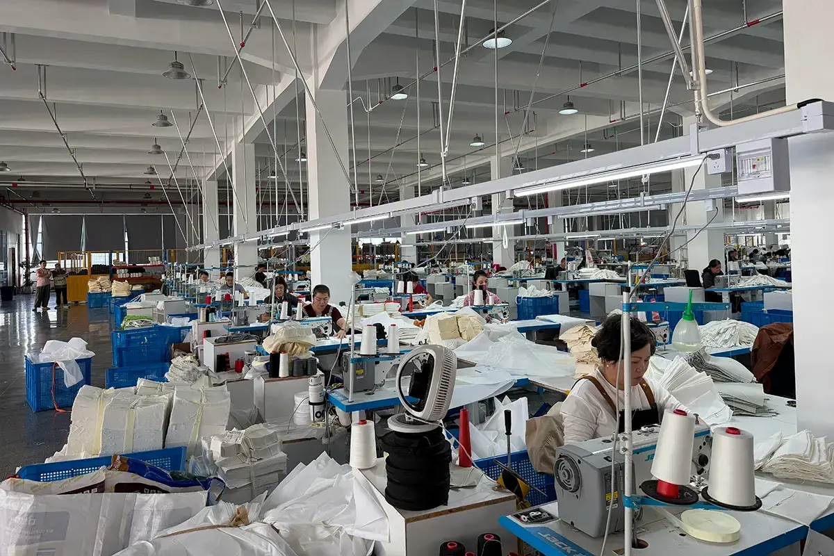 Bright zipper tote workshop with rows of industrial sewing stations.