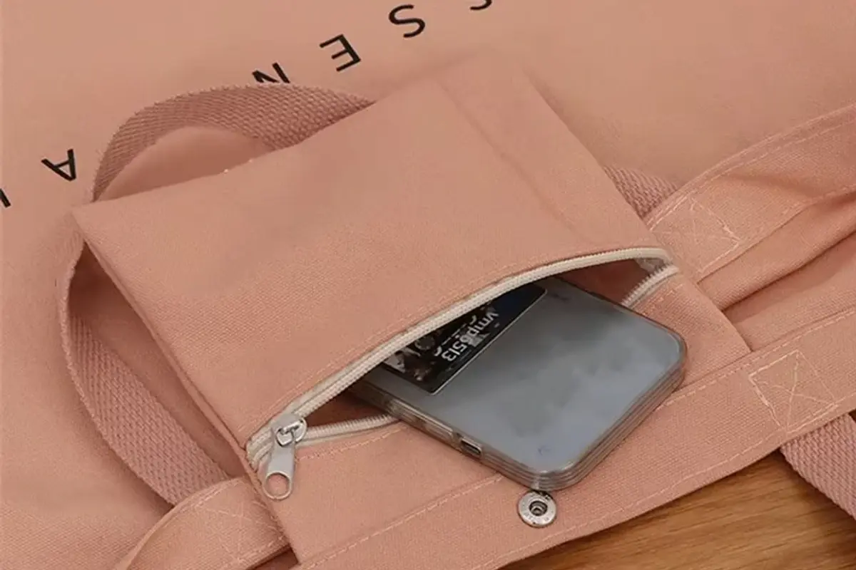Close-up of a zipper pocket on a pink canvas tote bag.