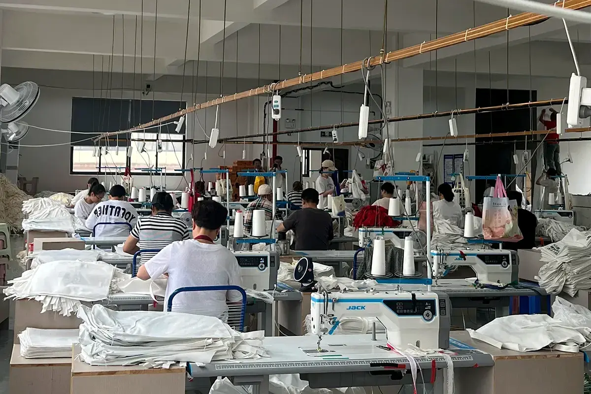 Sewing team assembling canvas tote bags across the production floor.