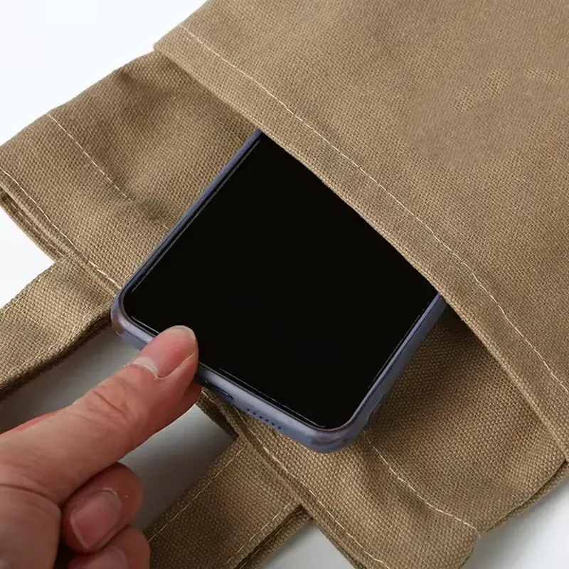 Heavy canvas tote inner pocket holding a mobile phone