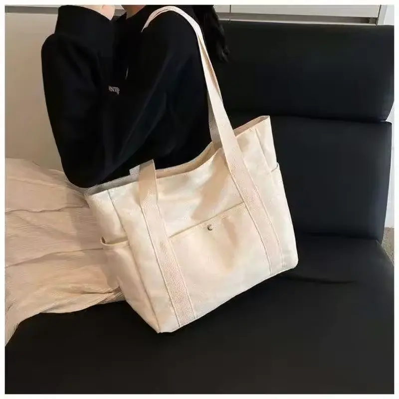 Beige canvas zipper tote with front pockets and reinforced handles