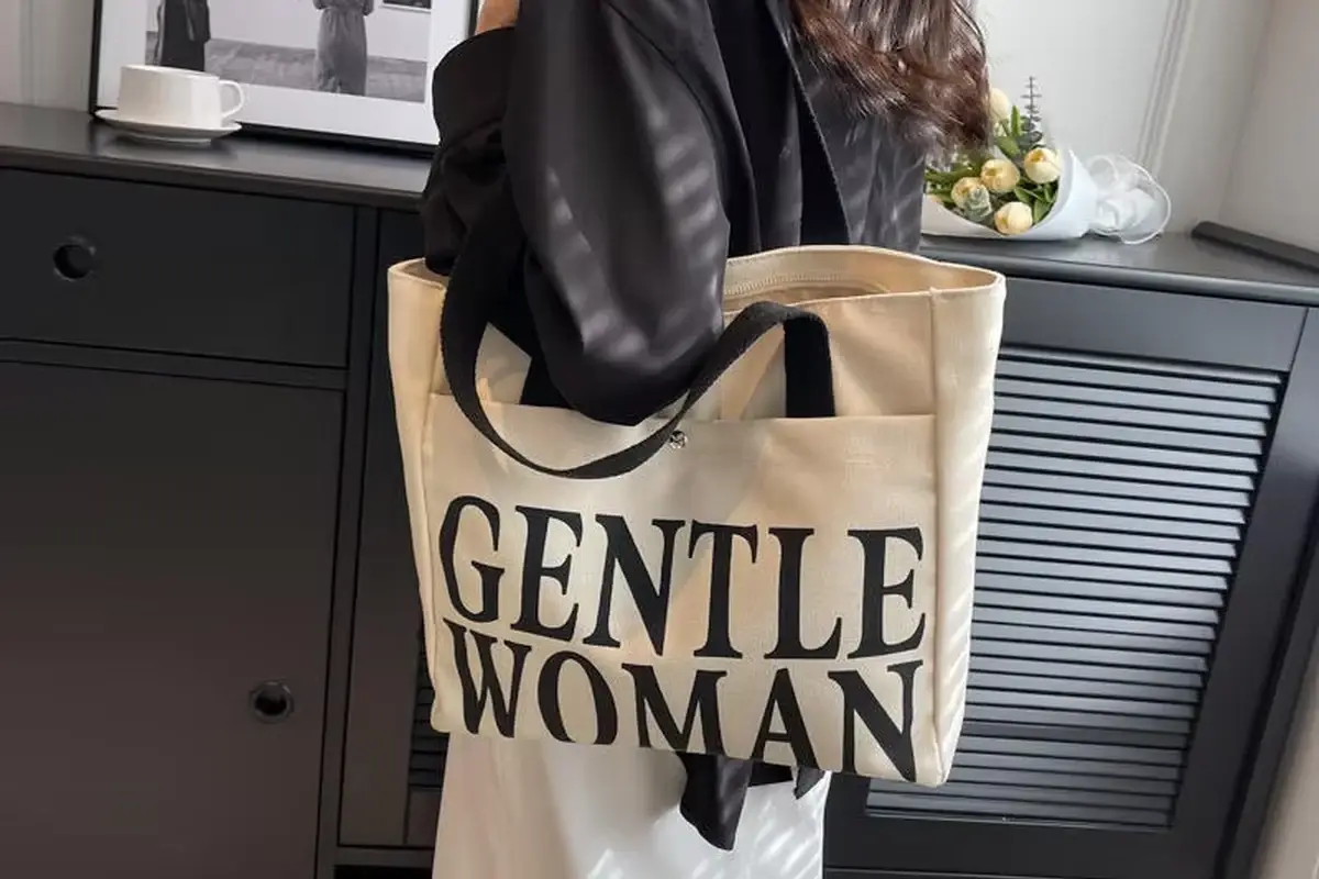 Natural canvas tote with black handles held open during use