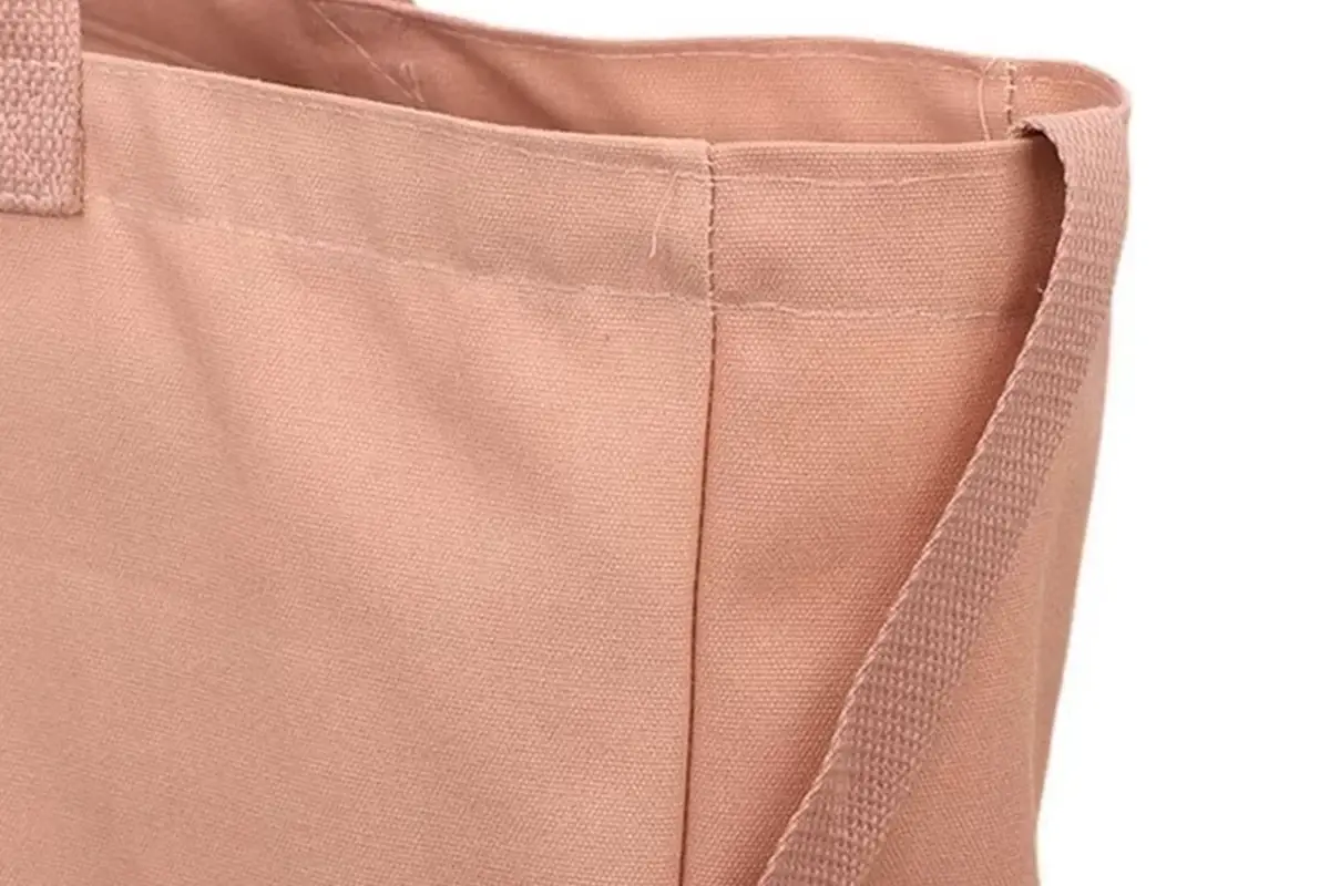 Close view of a pink canvas tote showing the zipper tape and seam