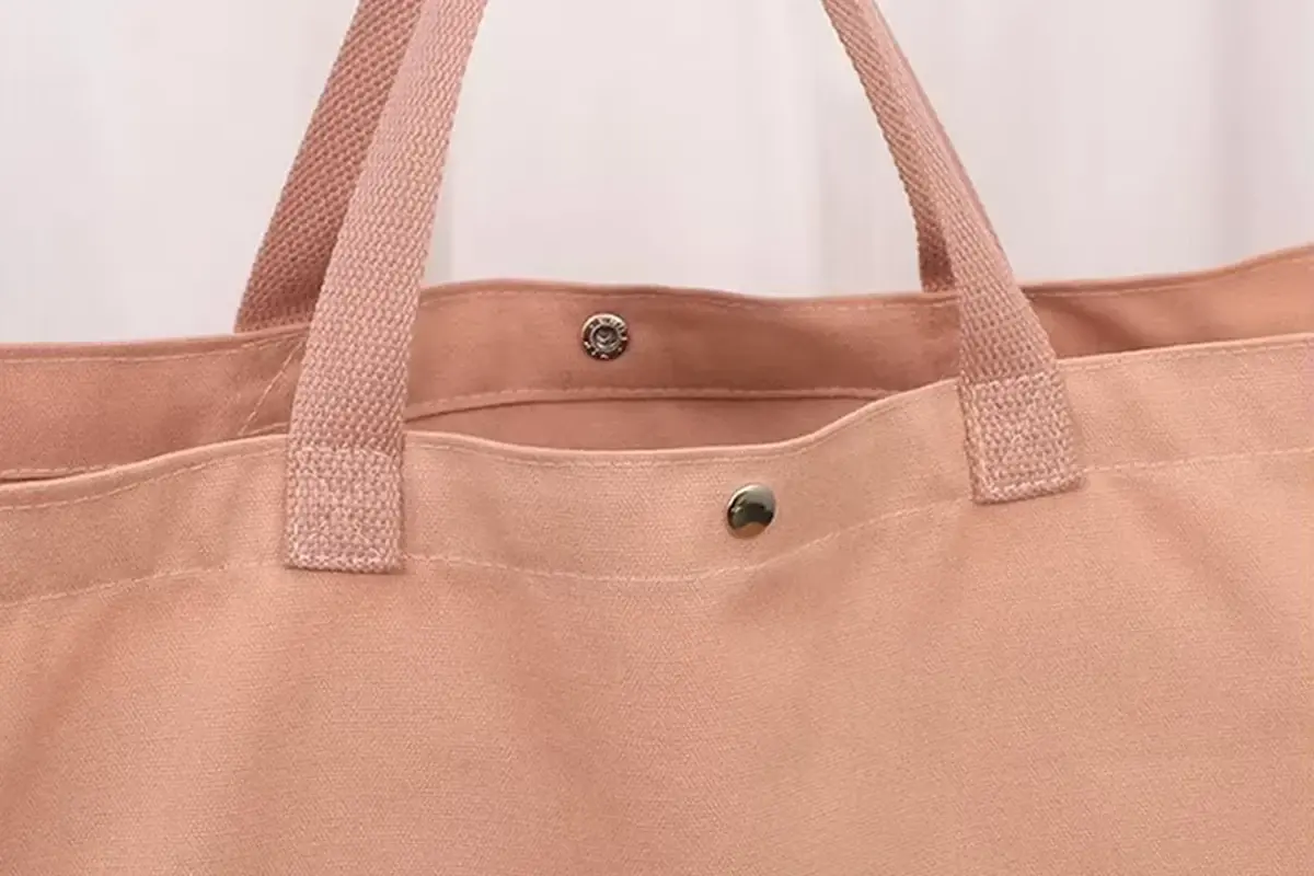 Pink canvas tote top showing handle seams and metal snap closures
