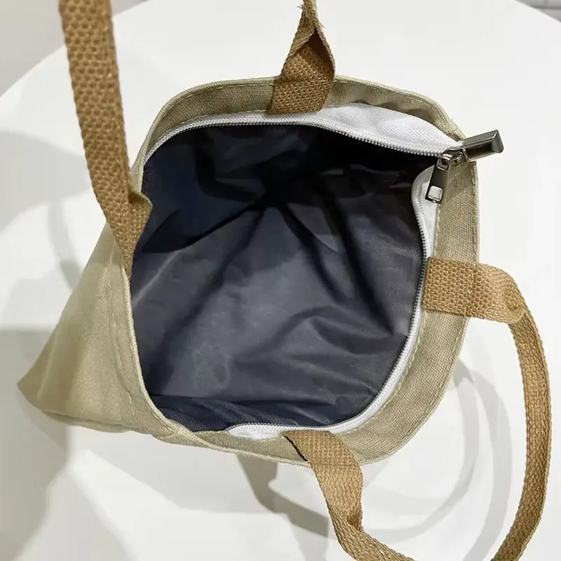 Beige canvas tote opened to show a dark lining and top zipper