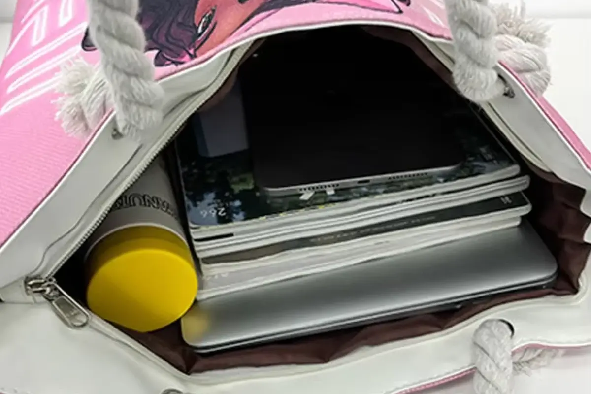 Open pink canvas zipper tote packed with notebooks and a bottle