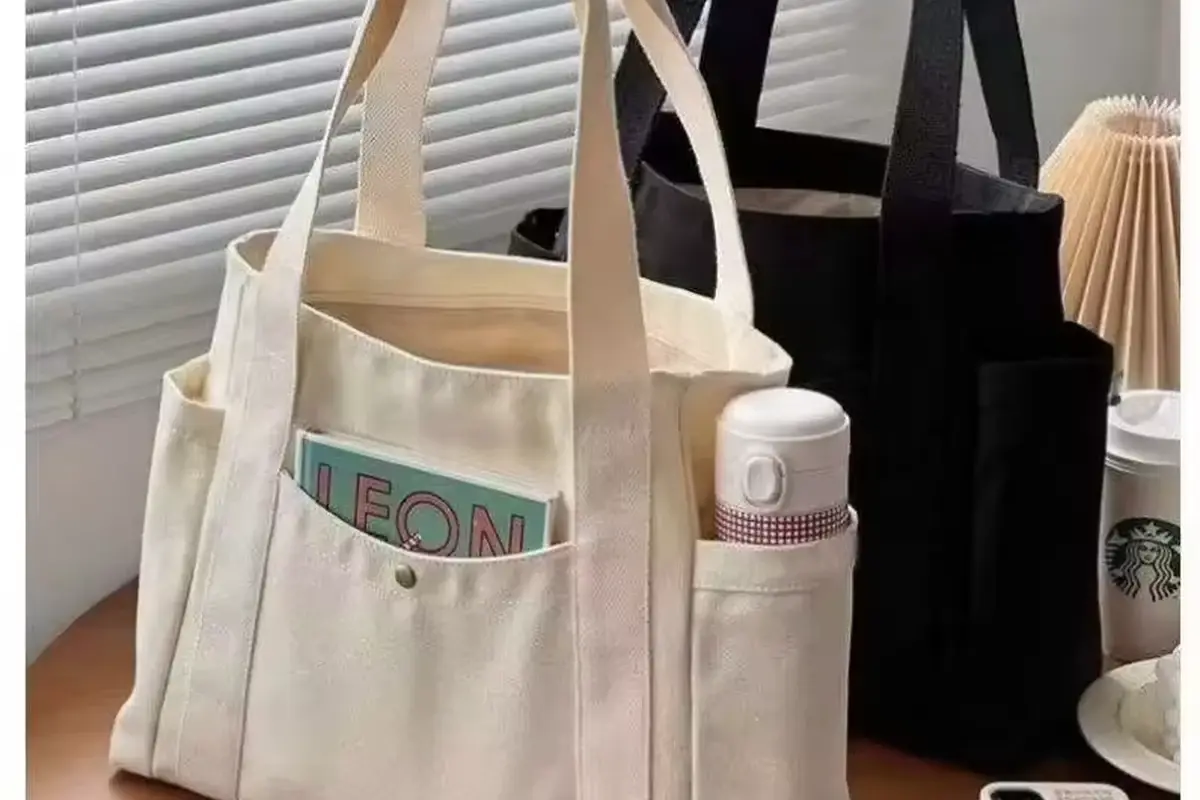 Natural cotton shopping tote with pockets holding books and a bottle