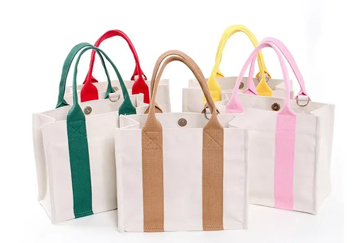 Canvas zipper totes lined up with five colored webbing trims