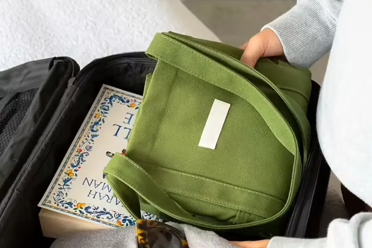 Folded green canvas tote placed inside an open suitcase