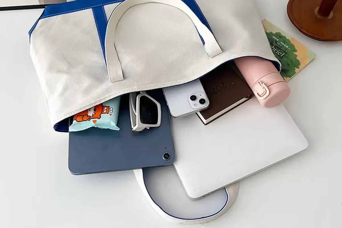 Open canvas zipper tote packed with a tablet notebooks and bottle