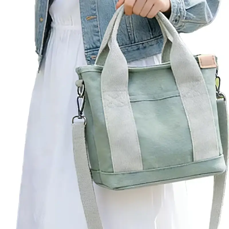 Sage canvas zipper tote carried by hand with a shoulder strap