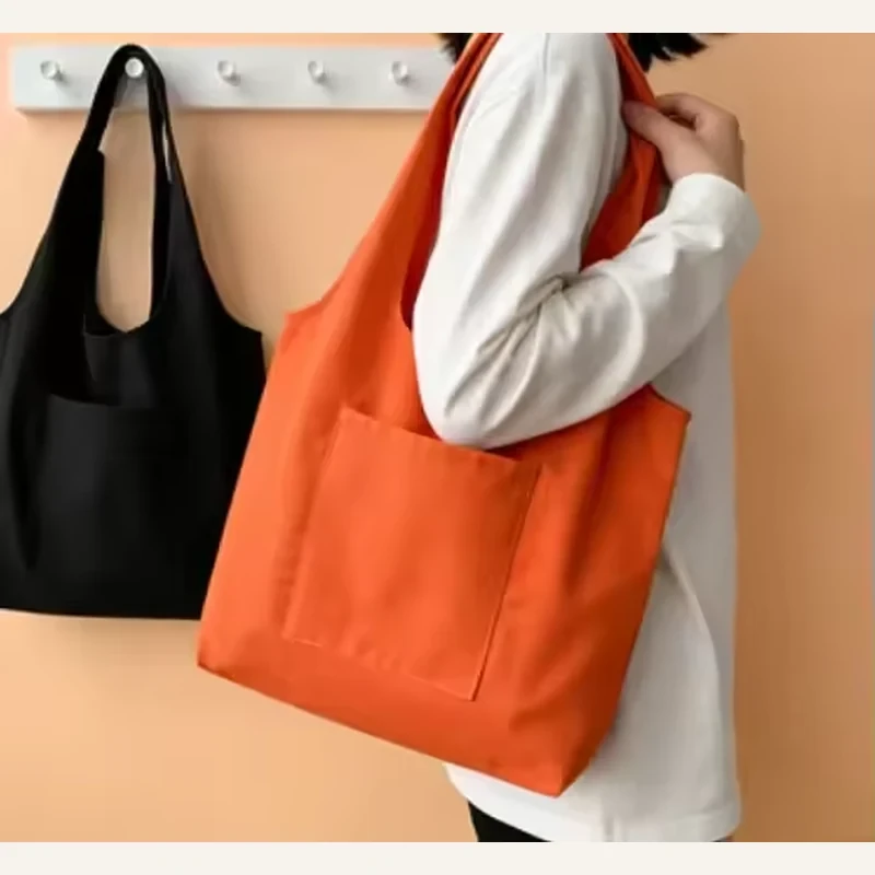 Black and orange lightweight cotton totes carried by a model