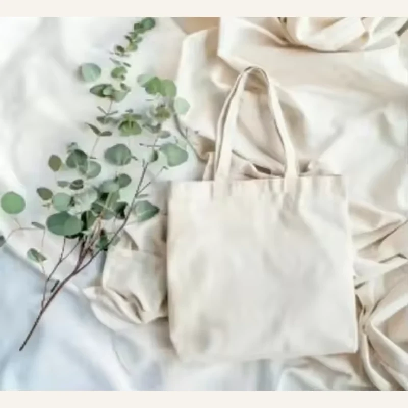Plain natural cotton tote bags arranged on soft folded fabric