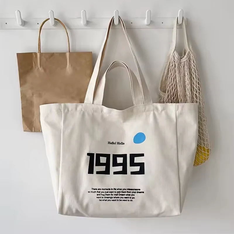 Natural cotton shopping tote with blue 1995 artwork and long handles