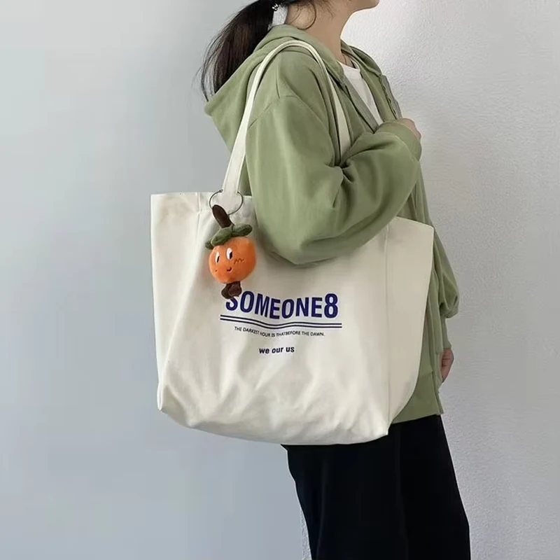 Natural cotton tote with blue lettering carried over the shoulder