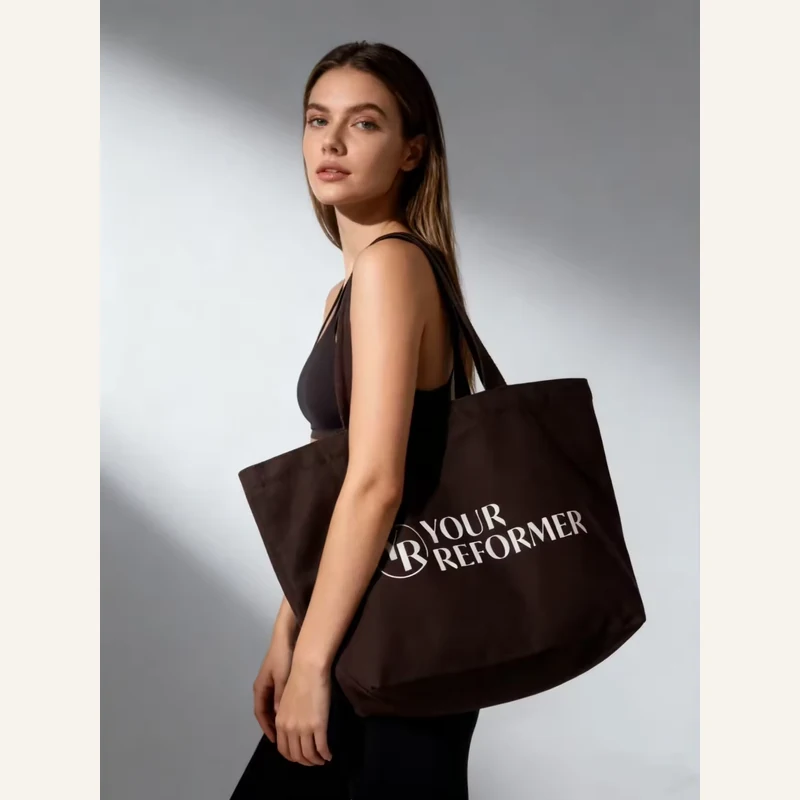 Brown classic canvas tote carried by a model with short handles